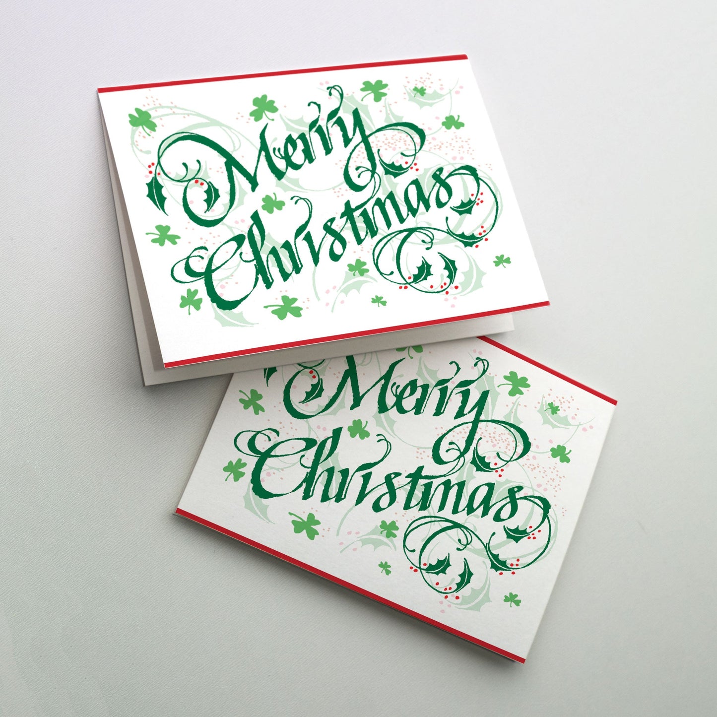 Merry Christmas in festive green lettering surrounded by holly leaves and shamrocks.