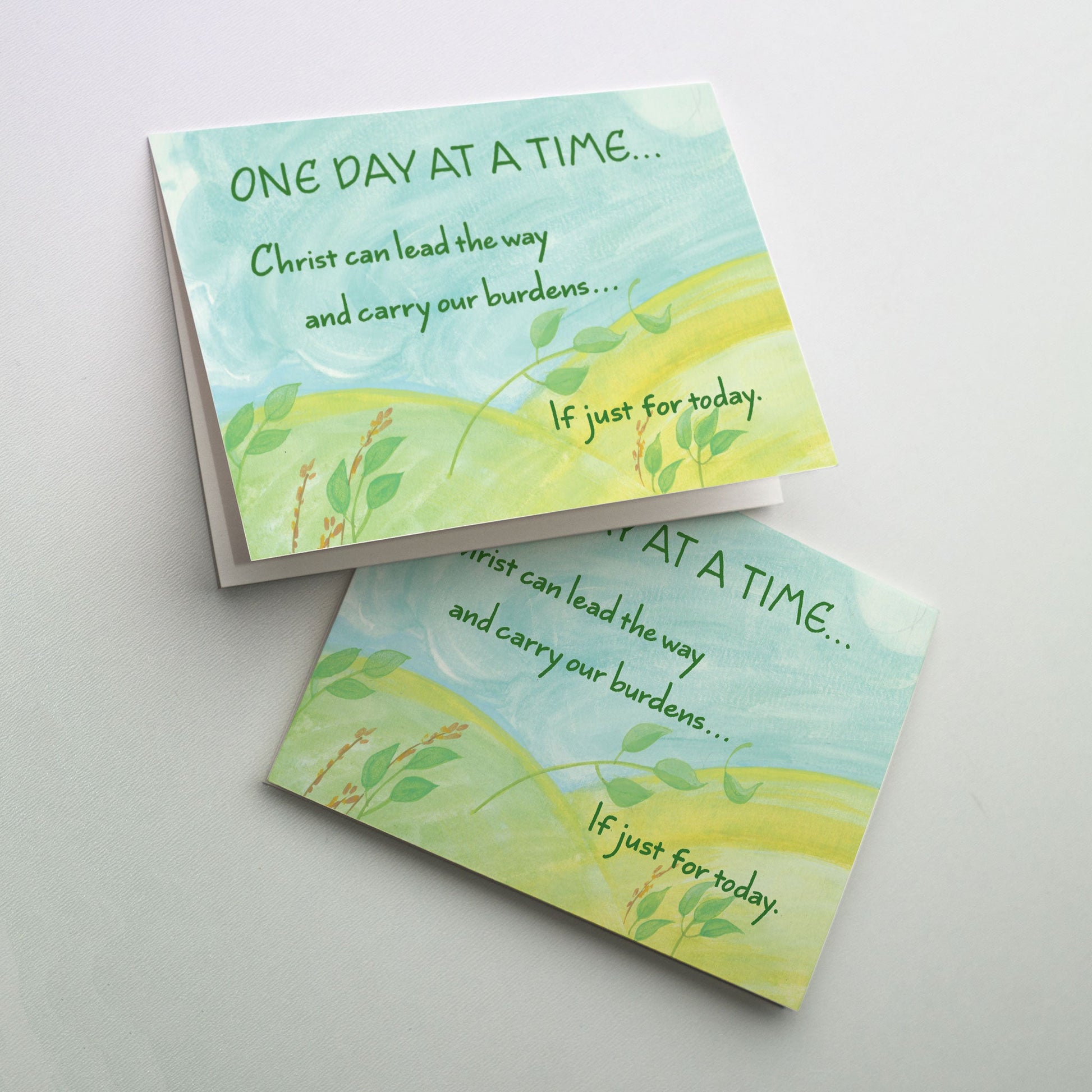 Watercolor of a windy sky over a green landscape of two hills with small green plants bending in the wind. The cards in &ldquo;One Day at a Time&rdquo; are reminders that God is there each step of the way during recovery, whether it&rsquo;s rehab through a 12-step program or recovery from knee or hip surgery.
